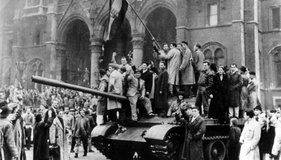 OPPSTANDEN I UNGARN: Budapest 1 november 1956. Fra den store oppstanden i Ungarn der innbyggere i Budapest hever det ungarske flagget på en kapret russisk panservogn. De ungarske frihetskjemperne sto på til det siste for å frigjøre seg fra Sovjetunionen. Stasminister Imre Nagy ble avsatt, og ført bort av sovjetiske soldater. Sovjet led store nederlag men, gjenvant makten tilslutt. Arkivfoto SCANPIX/Sverige, NTB.