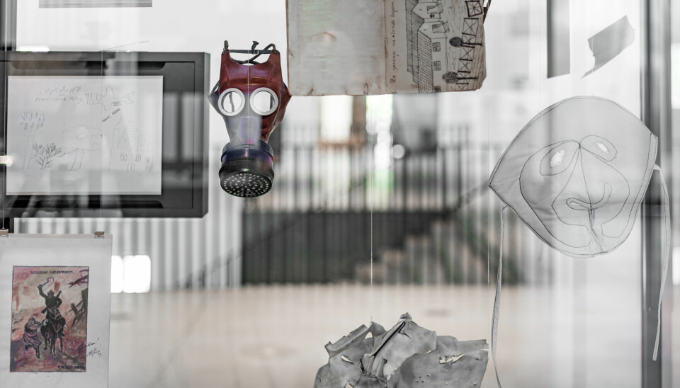Bilde som viser gassmaske og andre gjenstander som henger i på en glassplate som del av en utstilling