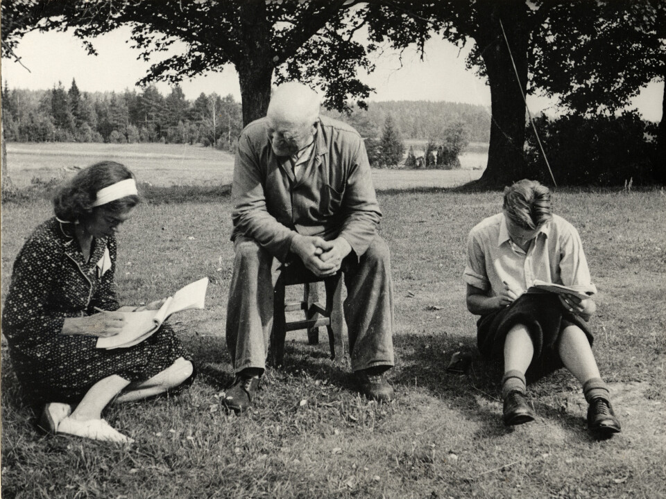 Bilde som viser en eldre informant som gir norskstudenter fra Oslo den språklige nøkkelen til Ål-dialekten. Bildet er tatt på en av de mange reisene Norsk målførearkiv hadde på 1950-tallet.