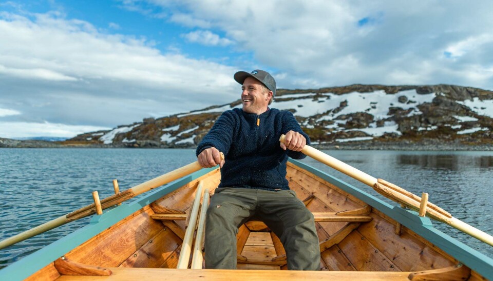 Ove Stødle er daglig leder av Mearrasiida – det sjøsamiske kultursenteret i Billefjord i Porsanger. Bildet viser en ung mann som sitter ved årene i en trebåt. Han er ute på sjøen og bak ham ser vi et snødekket landskap.
