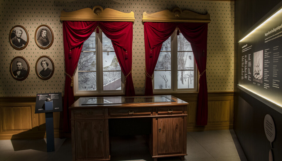 Kaptein Crawfurds dagbok skal stilles ut i utstillingen «De hvide Seil» på KUBEN som omhandler Sørlandets siste seilskutetid. Bildet viser et rom i en utsilling. Vi ser to høye vinduer med røde gardiner, fire portretter i runde rammer på veggen og et massivs skrivebord i eik foran vinduene.