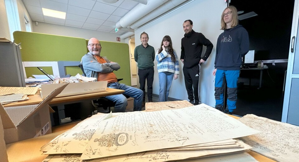 I ARKIVET: Historiestudentar på omvisning i IKA Møre og Romsdal. Her hos Gudmund Valderhaug. Fire personer står, en sitter og på bordet foran oss ser vi en bunke gamle håndskrevne dokumenter