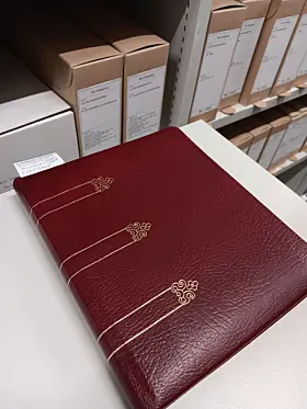 Bildet viser en bok som er innbundet i rødt skinn med gulldetaljer