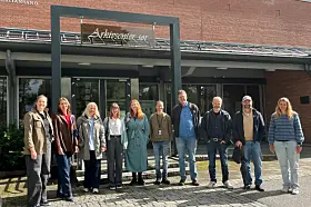 Gruppebilde av 10 kvinner og menn uten for et bygg det står Arkivsenter sør på et skilt bak dem