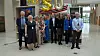 En gruppe mennesker står på rekke i en lys hall med gullfargede ballonger i bakgrunnen.