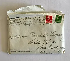 Gammel brevkonvolutt med håndskrevet adresse, poststempler og rødt og grønt frimerke.